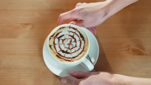 Female Hands Putting Coffee Cup on the Table Top View