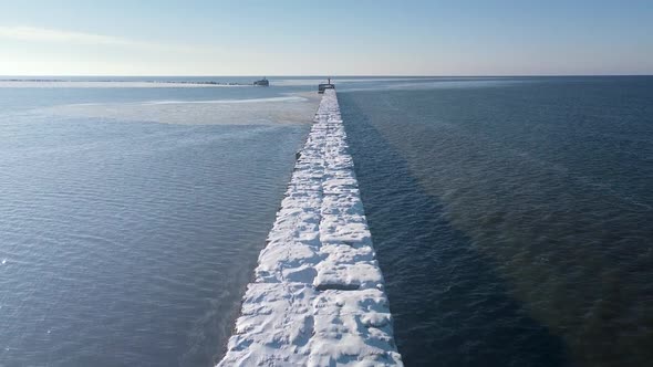 Aerial view of snow and ice covered concrete pier in the calm Baltic sea, Port of Liepaja on a sunny