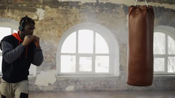 Afro American Young Male Boxer Practicing Shadow Boxing in Headphones in Bright Hall