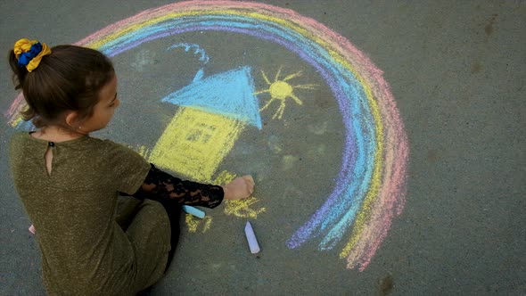 A Child Draws the Ukrainian Flag with Chalk on the Pavement