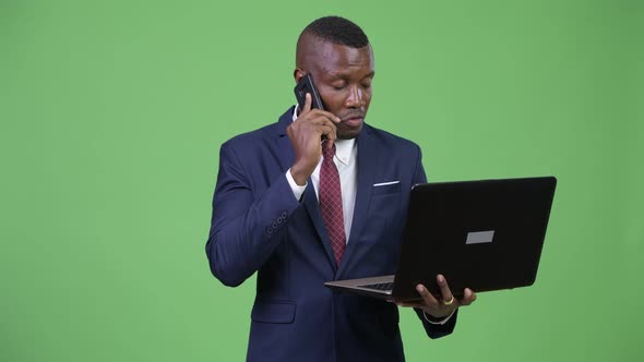 Young Happy African Businessman Talking on the Phone While Using Laptop