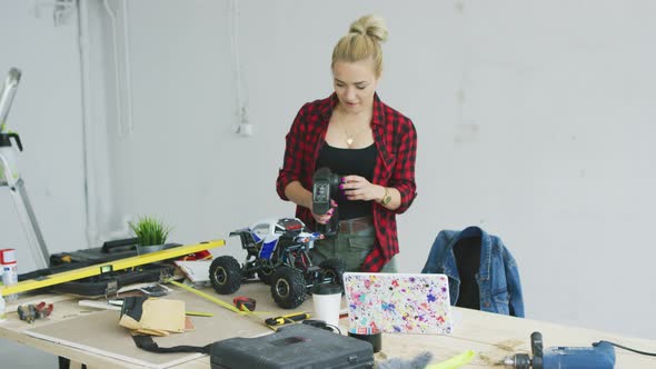 Woman Playing with Radiocontrolled Car in Workshop