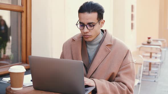 Positive Arabian man working with laptop in cafe