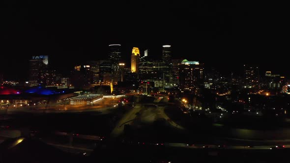 Aerial footage of downtown Minneapolis at night, traffic crossing by