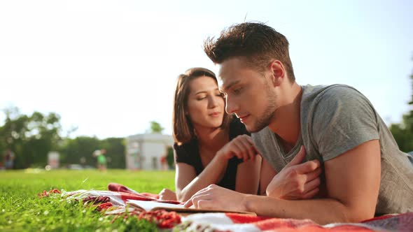 Young Beautiful Couple Reading Book Smiling Resting in Park