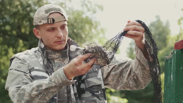 Closeup of a Man Fisher Who Caught a Fish in an Ambush Net and Looking at It