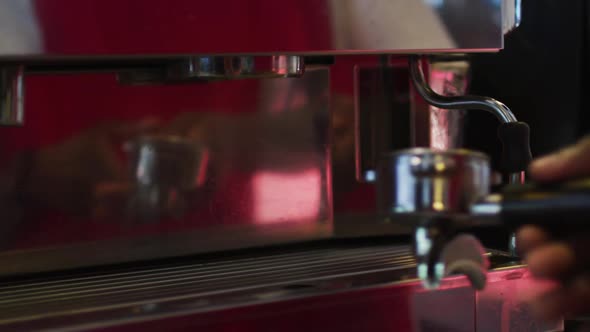 Midsection of african american male barista making coffee in coffee machine