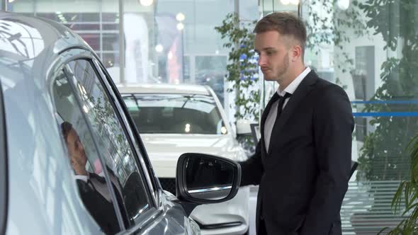 Young Businessman in a Suit Examining Cars for Sale at the Dealership