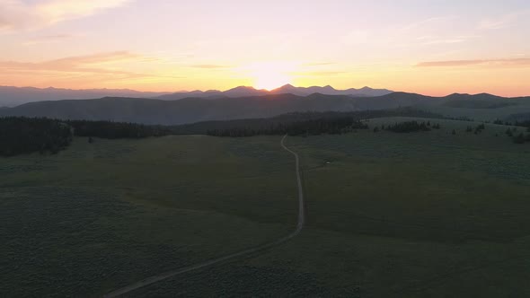 Flying high over meadow during sunset viewing dirt road