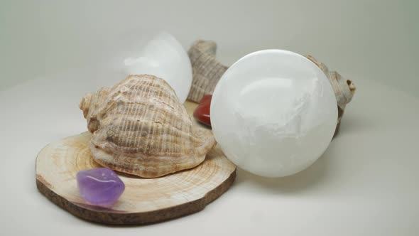 Sea Shells Sitting On Top Of A Wooden Craft With Two Crystal Balls And Small Gem Stones In Between -