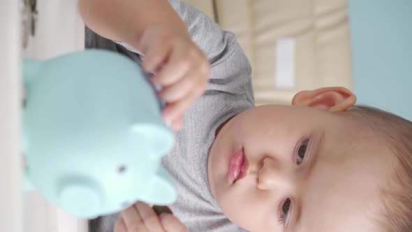 Toddler 12-17 months old throws a ruble coin into a blue piggy bank