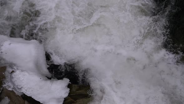 Mountain Creek and Stone Rapids with Snow. Rapid Flow of Water. Winter Waterfall. Slow Motion