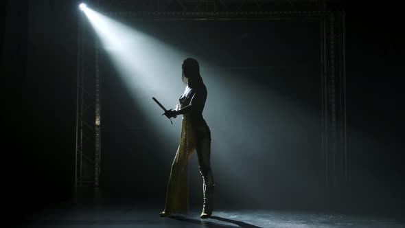 Silhouette of Dancing Joan of Arc with Bow and Arrow on Stage in a Dark Studio with Smoke and Neon