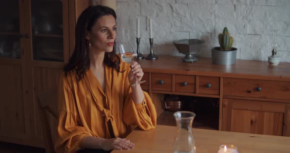 Beautiful Woman in a Yellow Blouse Drinks Water at the Table