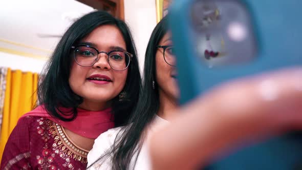 Two Young Indian Girls In Traditional Clothes And Eyeglasses Taking Selfies Together With A