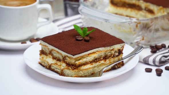 Traditional Italian Tiramisu dessert in glass baking dish, portion on plate and cup of coffee