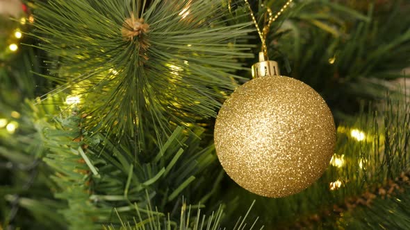 Golden color bauble with sequins on the artificial tree 4K 2160p 30fps UltraHD footage - Fairy-light