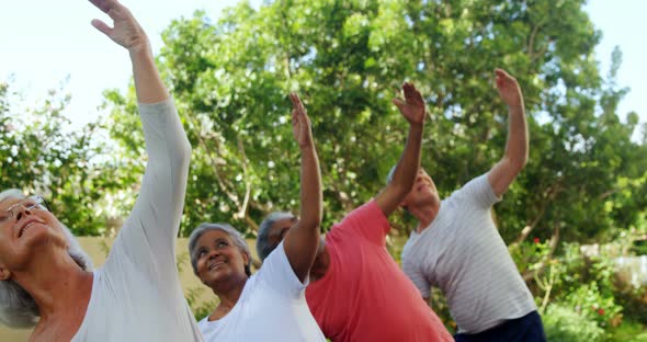 Senior friends doing stretching exercise in garden 4k