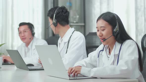 A Woman Doctors Working As Call Centre Agents Speaking To Customers While Her Colleagues Are Talking