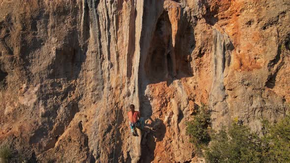 Slow Motion Footage of Man Rock Climber with Long Hair Hanging on Rope and Going Down After