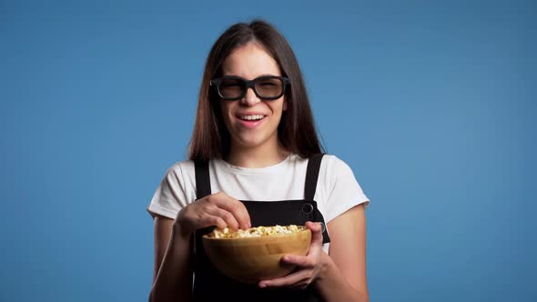 Young Asian Girl in 3d Glasses Watching Fascinating Comedy Movie,laughing and Eating Popcorn on Blue