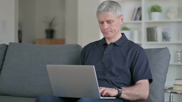 Cheerful Middle Aged Businessman with Laptop Doing Thumbs Up