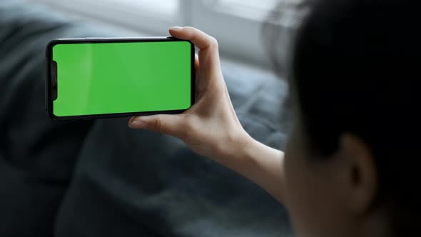 Close Up A Woman's Hand Holds A Smartphone With A Green Screen For Chromakey