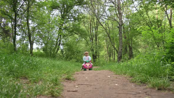 Child Riding a Toy Car in the Forest Park