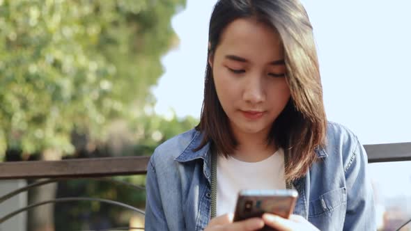 Young Asian female tourists scrolling feeds on smartphone social media communication.