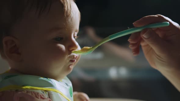 Portrait of Messy and Dirty Baby Boy Eating Soup From Spoon in Bed at Night