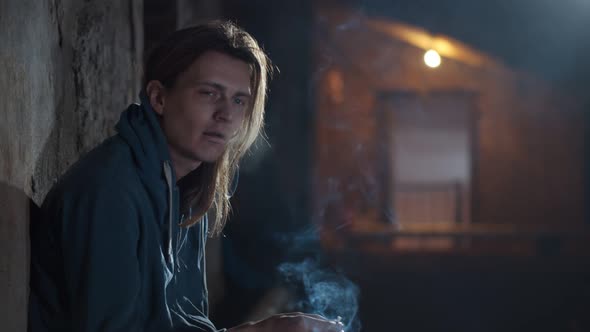 Junkie Man Leaning on Wall and Smoking in Abandoned Building