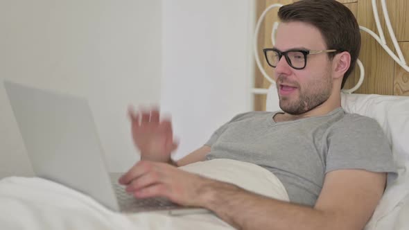 Beard Young Man Doing Video Chat on Laptop in Bed