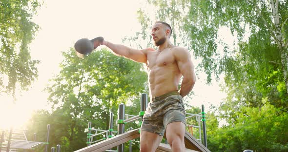 Man Doing Workout Exercise Lifting Kettlebell on Sports Ground