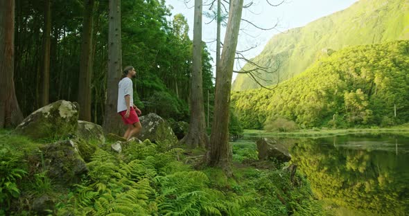 Caucasian Man Enjoys Beautiful Panoramic View of the Lake Surrounded with Plants