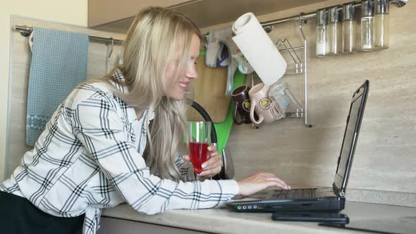 Woman Works Behind Laptop in Kitchen