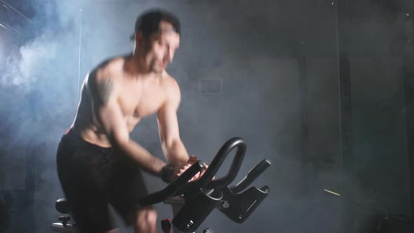 Strong White Athletic Man Shirtless Training in a Bicycle Simulator in the Gym.