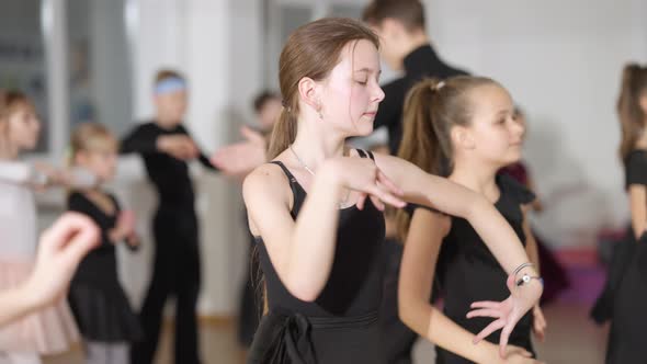 Concentrated Caucasian Girl Rehearsing Latin Ballroom Dance Movements with Classmates in Dancing