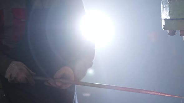 Man Blacksmith Thinning a Hot Oblong Piece of Metal Under an Automatic Press