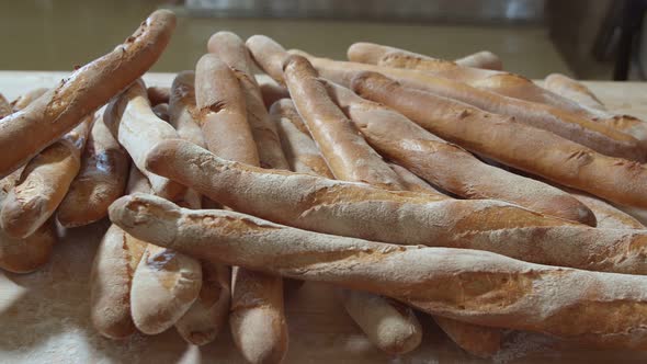 Fresh Baked Long Baguette Breads Lie on the Wooden Table Sprinkled with Flour in a Pile