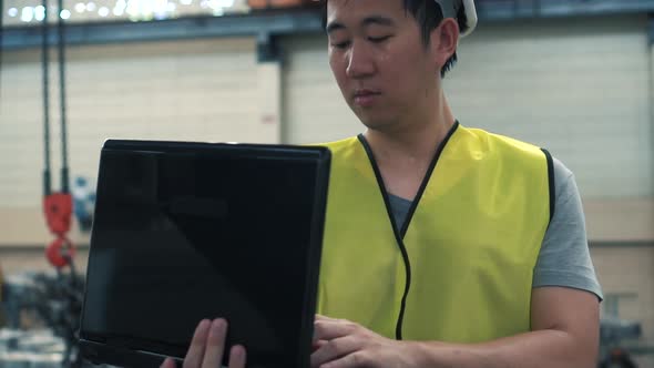 Industrial Engineer with Hard Hat Working with Laptop at Factory