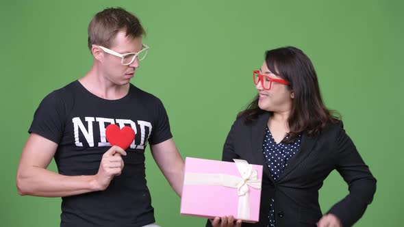 Mature Asian Businesswoman and Young Scandinavian Nerd Man Celebrating Valentine's Day Together