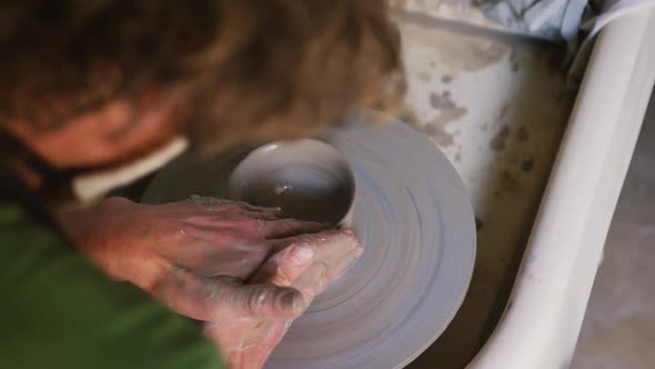 Close up view of male potter creating pottery on on potters wheel at pottery studio