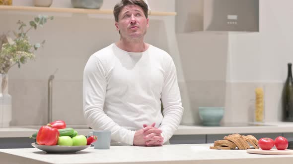 Serious Middle Aged Man Thinking While Standing in Kitchen