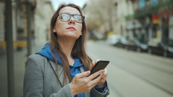 Woman Stands at a Public Transport Stop and Checks the Timetable