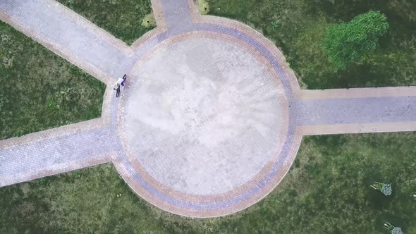 Top view of a bicycle woman riding a bicycle on a circular road in a city park.