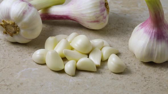 Fresh peeled garlic cloves with whole bulbs in the background