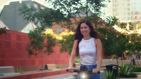 Asian Woman Drive Electric Bike Outdoors