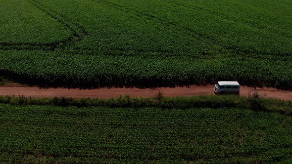 Van driving down a dirt road through a rural, farm landscape - aerial view