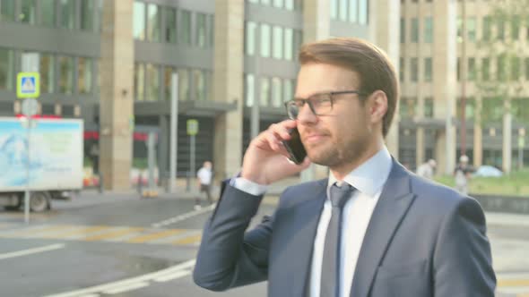 Businessman Talking on Phone while Walking in Street