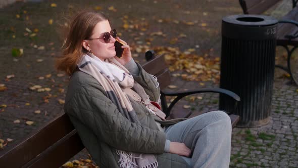 Woman Have a Talk By Smartphone Sitting on the Bench in the Street of Old Town  60p